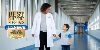 Un profesional médico que sostiene a niños pequeños de la mano.